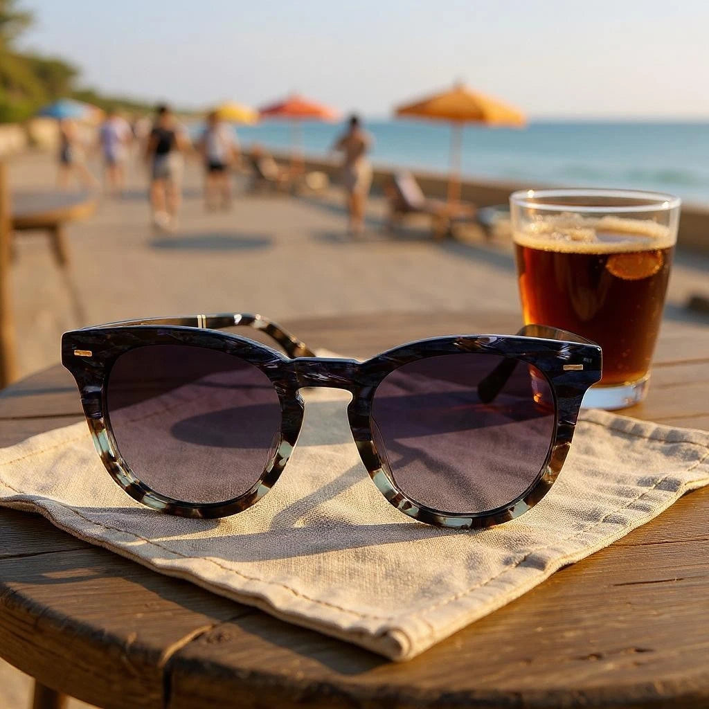 Sunglasses and a glass of beer on a table with a beach background