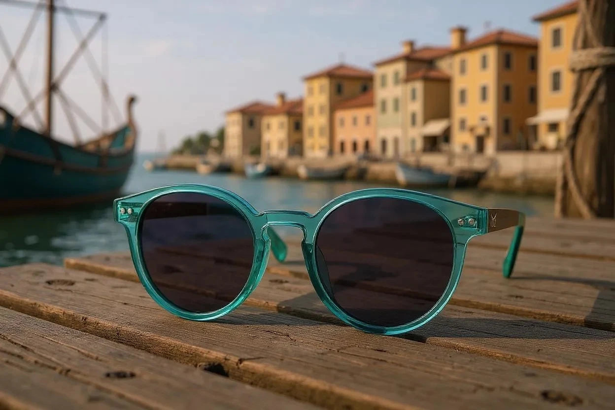 Teal sunglasses on a wooden surface with a harbor and buildings in the background