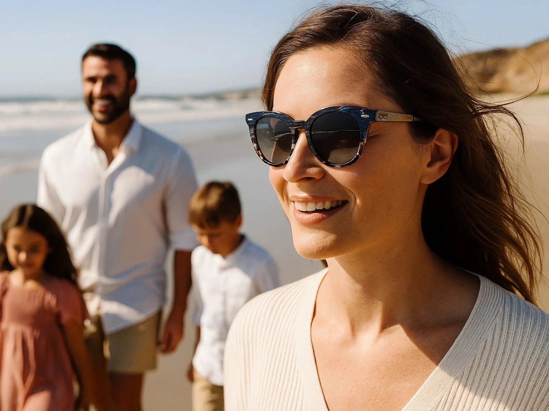 Woman wearing sunglasses with a family in the background on a beach